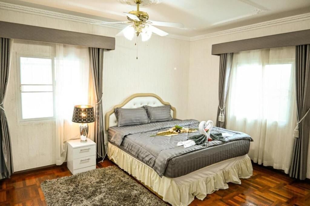 A bedroom with a bed, nightstand, lamp, and curtains.