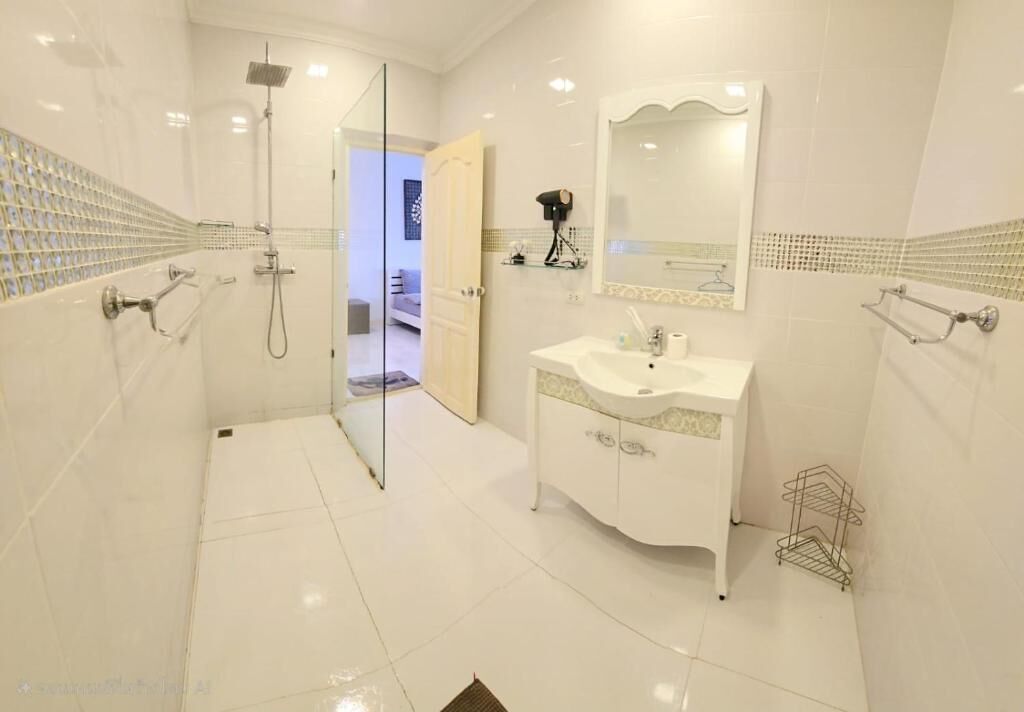 Un bagno moderno con cabina doccia in vetro, un lavabo con specchio e pavimento piastrellato.