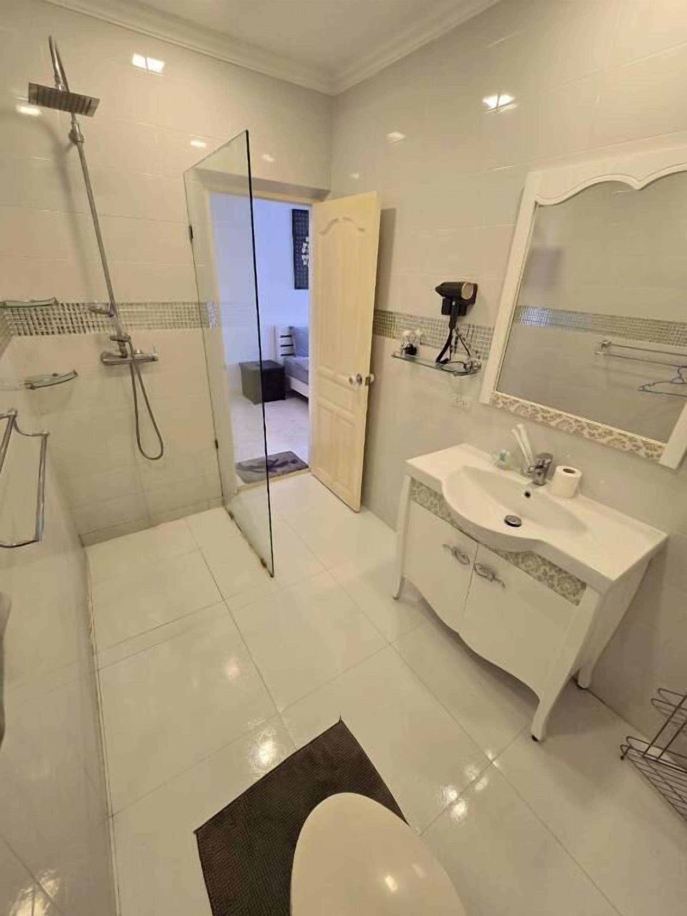 A modern bathroom with a glass shower enclosure, a white vanity with a mirror, and a toilet.