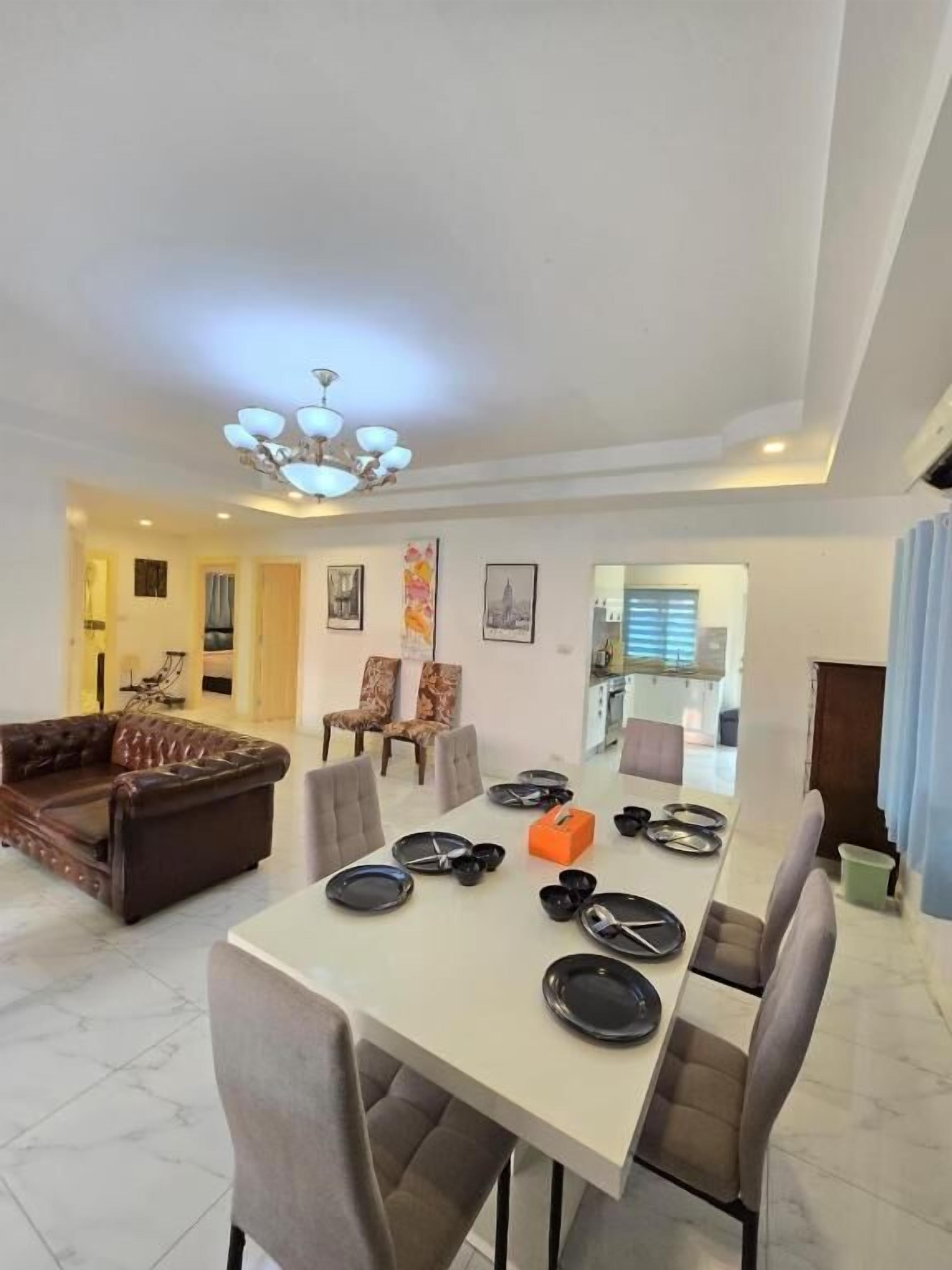 A dining area with a table set for six, surrounded by six chairs.