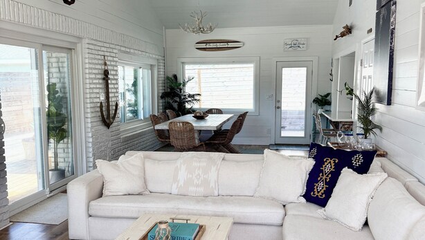 A spacious living room with a white sectional sofa, a wooden coffee table, and a chandelier. - Quiet Laguna Beach Home- 1  Block to Ocean - Pool & Spa-Pets - Games - Sleeps 14 (Panama City Beach)
