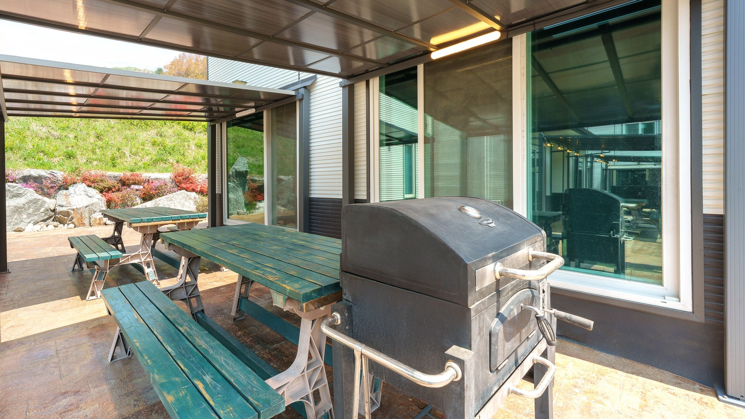 Un patio exterior con una parrilla, una mesa de picnic y bancos.