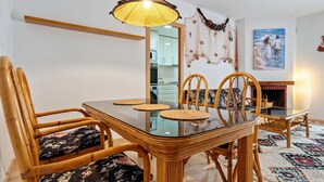 Un coin repas avec une table en verre, des chaises en osier et un luminaire suspendu.