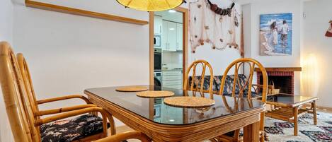 A dining area with a glass table, wicker chairs, and a hanging light fixture.