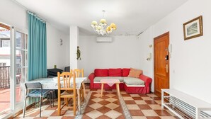 A room with a dining table, chairs, a red sofa, a patterned floor, a chandelier, and a door with a telephone. - Apartment 'Med Stor Terass' with Mountain View, Wi-Fi and Air Conditioning (Fuengirola)