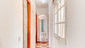A hallway with a checkered floor, wooden doors, and a window on the right. - Apartment 'Med Stor Terass' with Mountain View, Wi-Fi and Air Conditioning (Fuengirola)
