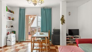 A living room with a TV, a dining area with a table and chairs, and a bookshelf with books and decorative items. - Apartment 'Med Stor Terass' with Mountain View, Wi-Fi and Air Conditioning (Fuengirola)