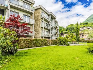 A modern apartment building with balconies, a stone facade, and a well-maintained garden. - Apartment Nancy by Interhome (Domaso)