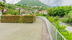 Un sentier pavé mène à un village perché sur une colline, avec des bâtiments et une montagne en arrière-plan.