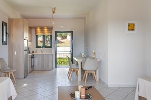 A modern kitchen with a dining area, a view through the door, and a table with candles.