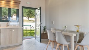 Une cuisine moderne avec un coin repas, une vue sur la verdure et une porte donnant sur un espace extérieur.