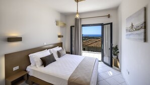 Une chambre à coucher avec un lit, des tables de chevet, un luminaire suspendu, une vue à travers une porte coulissante et un tableau au mur.