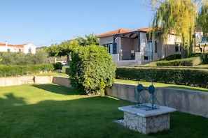 Un quartier résidentiel avec une pelouse bien entretenue, un banc en pierre et une maison avec un toit rouge.