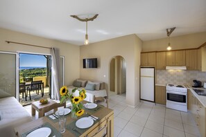 A modern kitchen with a dining area, a sofa, and a TV.