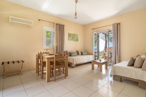 Una habitación con una mesa de comedor, sillas, un sofá, una mesita y una cama.