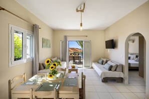 Una habitación con una mesa de comedor, sillas, un sofá y un televisor montado en la pared.