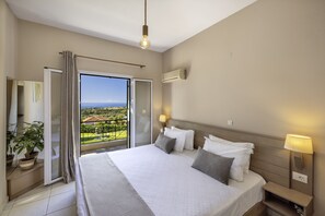 Ein Hotelzimmer mit einem großen Bett, einer Glastür zu einem Balkon, einer Wand-Klimaanlage und einer Nachttischlampe.