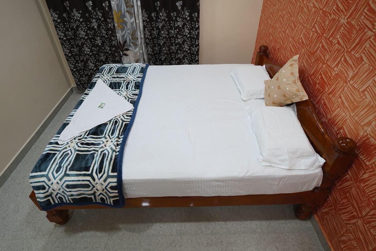 A neatly made bed with a patterned blanket, a pillow, and a folded towel.