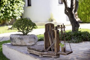 Une pompe à eau d’extérieur de style rustique, dotée d’une structure en bois, d’une base en pierre et d’une plante en pot.