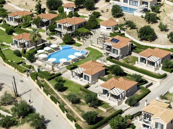 An aerial view of a residential area with houses, a swimming pool, and solar panels.