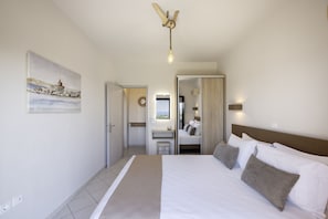 A hotel room with a bed, a desk, a chair, a mirror, and a painting on the wall.