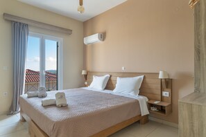 Une chambre d’hôtel comprenant un lit, une table de chevet, une lampe, un appareil de climatisation et une vue sur l’extérieur.