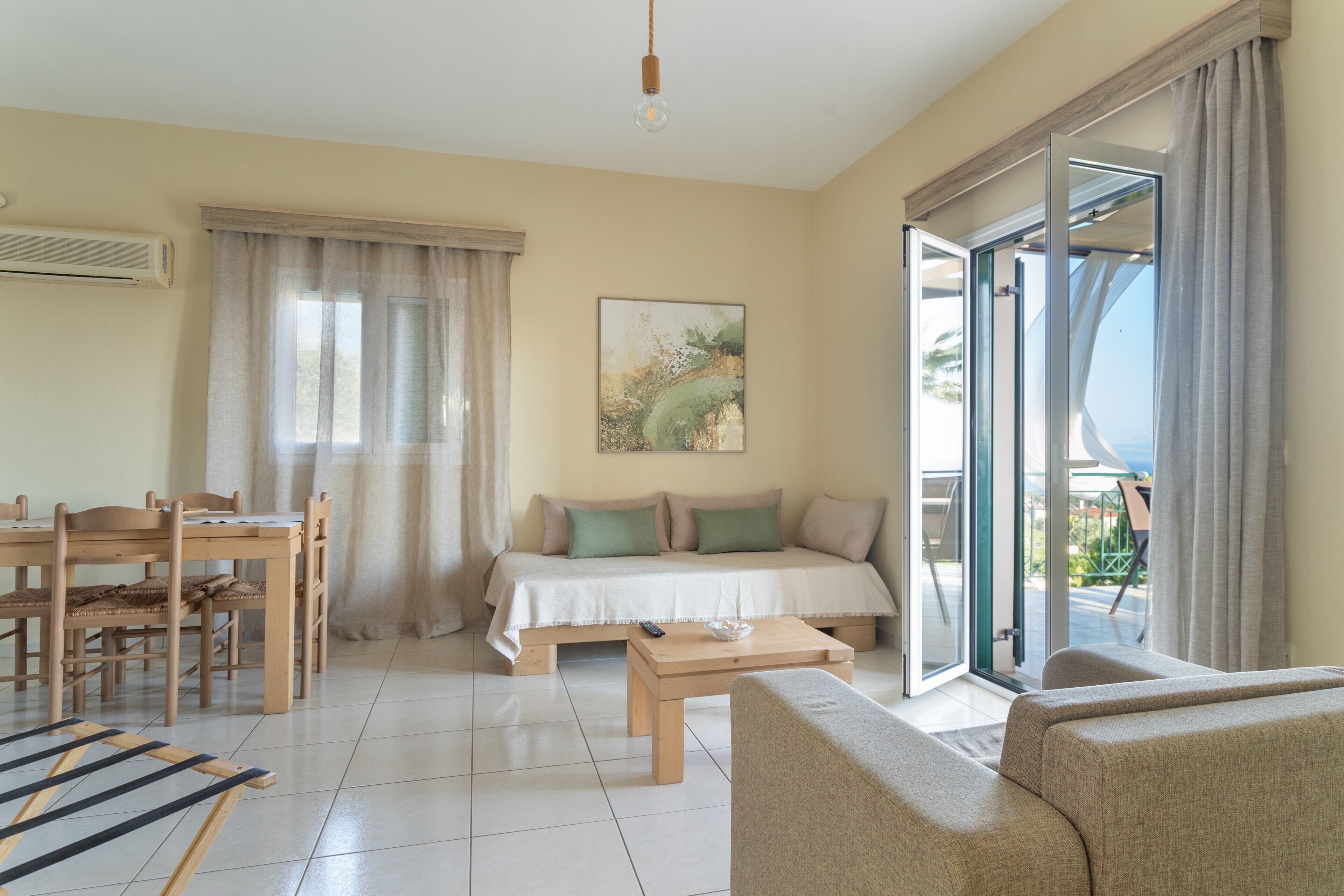 A room with a bed, a sofa, a dining table, and a balcony.
