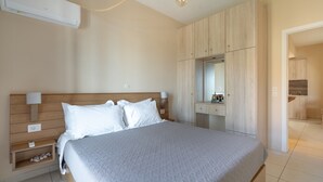 Un dormitorio con cama, mesitas de noche, armario, espejo y una kitchenette.