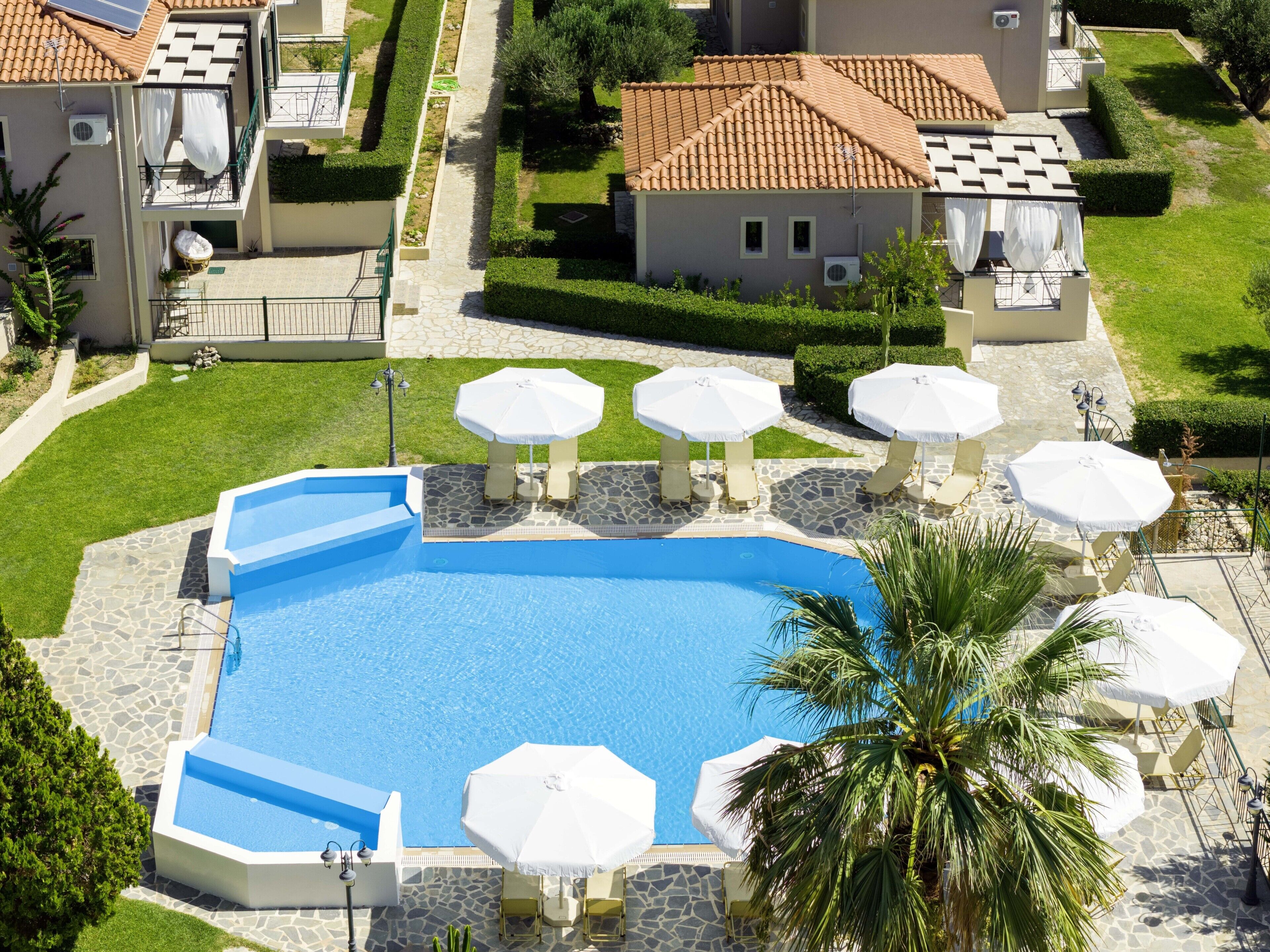 Une piscine entourée d’un sol en pierre, de parasols et de chaises longues.