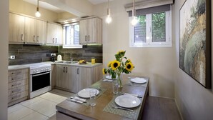 Una cocina moderna con armarios de madera, horno empotrado y comedor con mesa preparada para dos.
