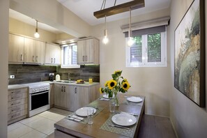Une cuisine moderne avec des meubles en bois, un four encastré et un coin repas avec une table dressée pour deux personnes.