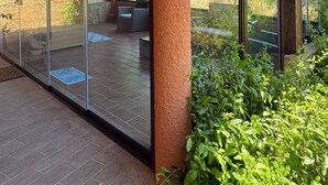A modern outdoor patio with glass doors, a wooden ceiling, and a view of a garden. - Villa 'Harmònia' with sea view, Wi-Fi and air conditioning (Villasimius)