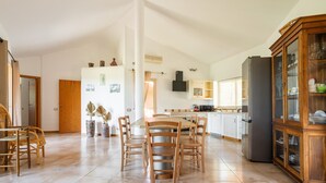 A spacious kitchen with a dining area, a large cabinet, and a refrigerator. - Villa 'Harmònia' with sea view, Wi-Fi and air conditioning (Villasimius)