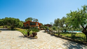 A stone-paved driveway leading to a house with a pool and outdoor seating area. - Villa 'Harmònia' with sea view, Wi-Fi and air conditioning (Villasimius)