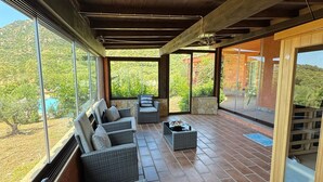 A covered patio with wicker furniture, a coffee table, and a view of a mountainous landscape. - Room 'Campus' with Sea View, Wi-Fi and Air Conditioning (Villasimius)