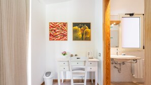 A bathroom with a white vanity, a mirror, and two framed pictures on the wall. - Room 'Campus' with Sea View, Wi-Fi and Air Conditioning (Villasimius)