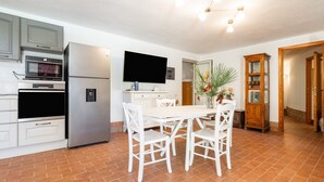 Une cuisine équipée d’une table à manger, de chaises, d’un téléviseur et d’un réfrigérateur.