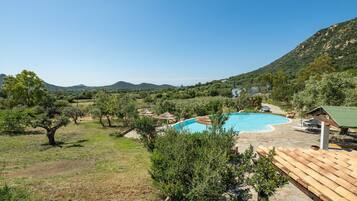 Ein Pool, umgeben von Bäumen, mit einem Berg im Hintergrund.