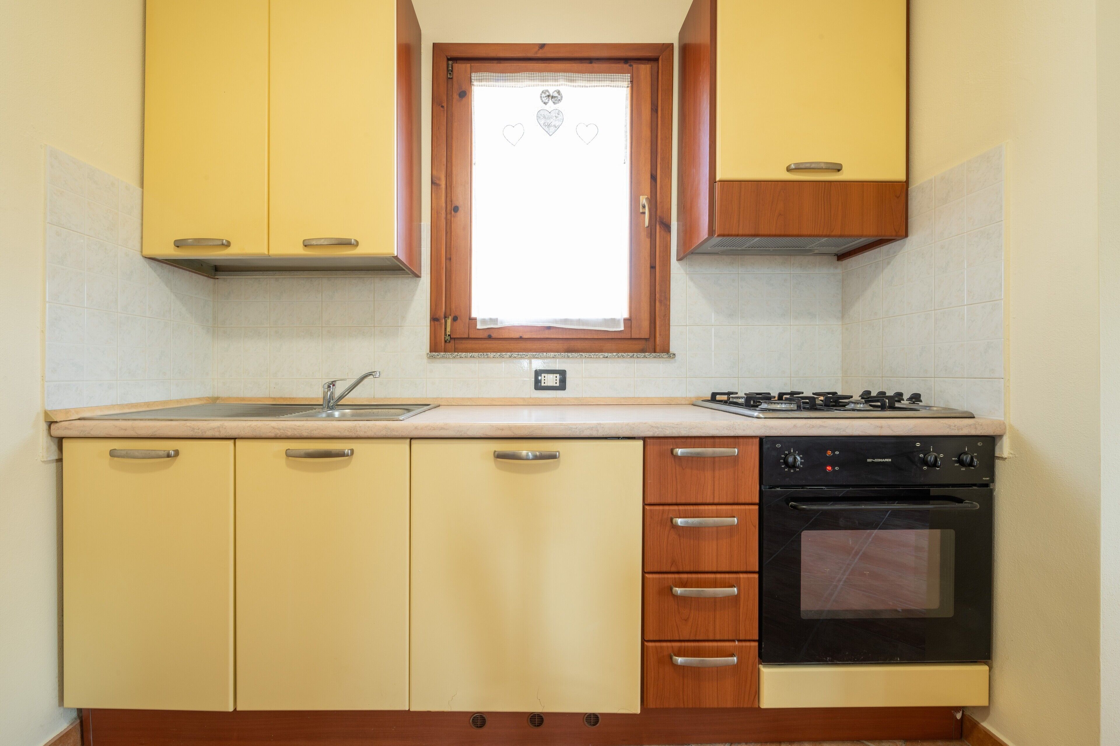 Una cucina con lavello, fornelli, forno e pensili in legno.