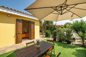 Une terrasse avec une table en bois, des chaises et un grand parasol.