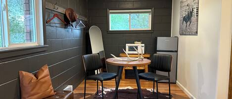 A compact kitchen with a dining area, featuring a wooden table, two chairs, a bench, and a cowhide rug.