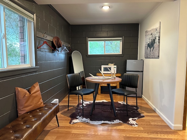 A compact kitchen with a dining area, featuring a wooden table, two chairs, a bench, and a cowhide rug. - Elk Antler Inn (Thermopolis)