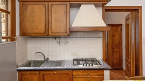 A kitchen with wooden cabinets, a gas stove, a sink, and a tiled backsplash.