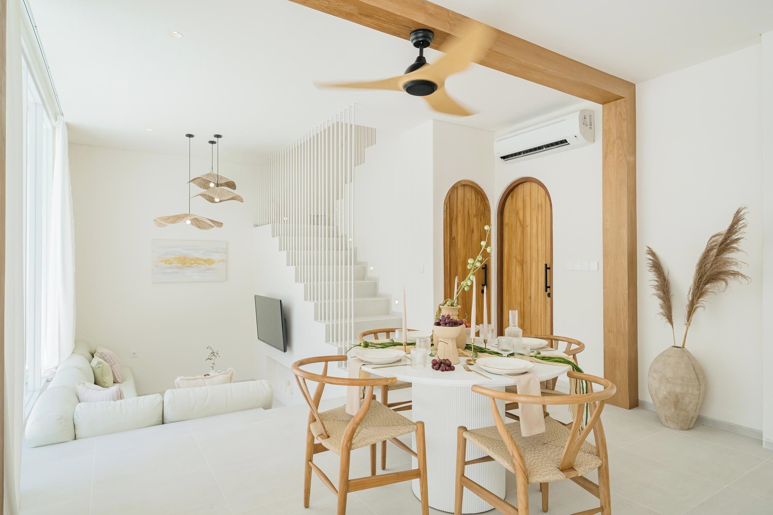 Un comedor moderno con una mesa redonda, sillas de madera y un ventilador de techo.