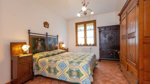 A bedroom with a bed, wooden wardrobe, and a window with curtains. - Apartment 'La Sassetta - Collina' with Private Garden (Bibbona)
