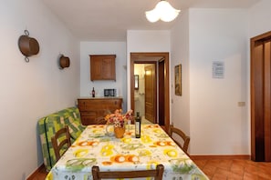 Un coin repas avec une table dressée pour deux personnes, un buffet en bois et un four à micro-ondes fixé au mur.