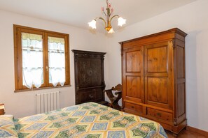Une chambre à coucher avec un lit, une armoire en bois, un radiateur et une fenêtre avec des rideaux.