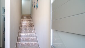 A marble staircase leading upwards, with a plain wall on the right and a door on the left. - Apartment 'Perla  1' with Shared Terrace, Wi-Fi and Air Conditioning (Pachino)
