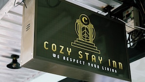 A sign for Cozy Stay Inn with a stylized 'C' logo and the text 'COZY STAY INN' and 'WE RESPECT YOUR LIVING'. - COZY STAY INN (Bangkok)