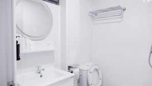 A modern bathroom with a sink, mirror, toilet, and shower. - COZY STAY INN (Bangkok)